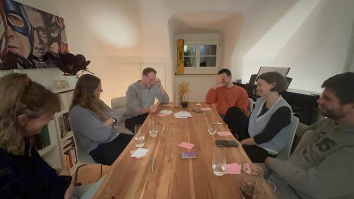 Friends laughing around a dinner table mid-game